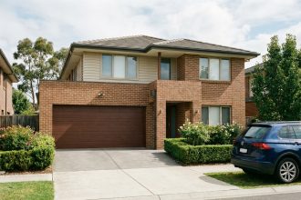 Maison résidentielle avec une porte de garage double en façade, allée pavée et jardin entretenu